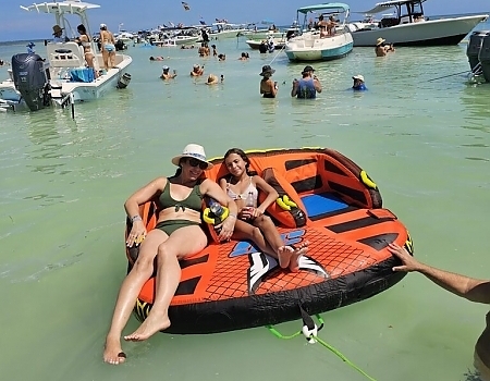 Two people relaxing on an inflatable raft in the water with boats in the background during Islamorada boat tours.