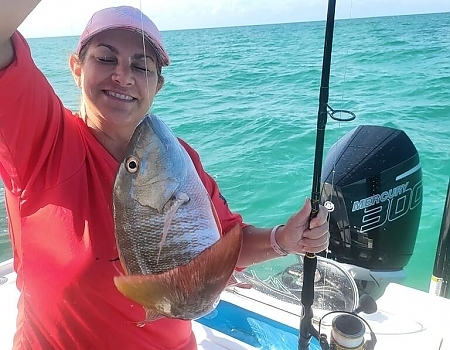 Woman holding a large fish on a boat in Key Largo with Beyond Blessed Charters.