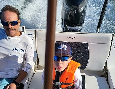 Man and child sitting on a boat with the ocean in the background during Islamorada boat tours.