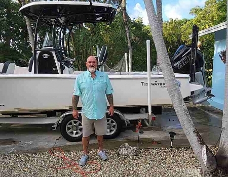 Man standing in front of a boat on a trailer in Key Largo.