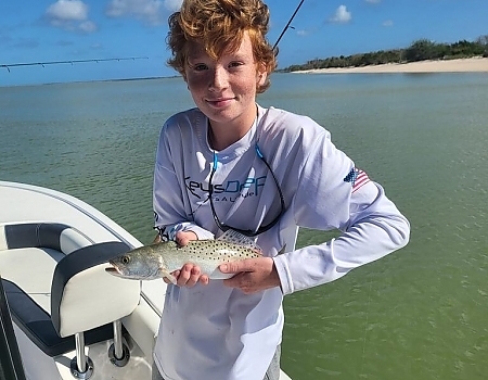 Boy holding a fish on a boat near the shore in Islamorada.
