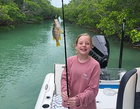 Girl holding a fish on a boat in a mangrove area in Islamorada.