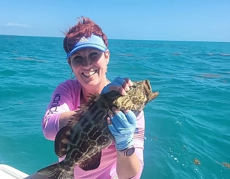 Woman holding a fish on a boat in Key Largo with Beyond Blessed Charters.