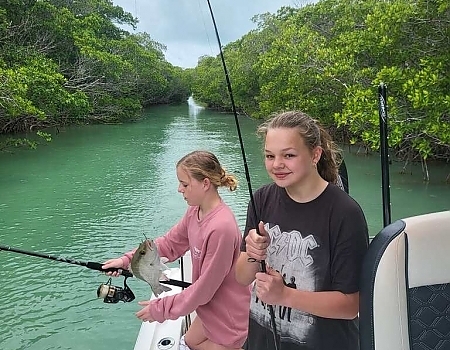 Two girls fishing on a boat in a mangrove area in Islamorada.