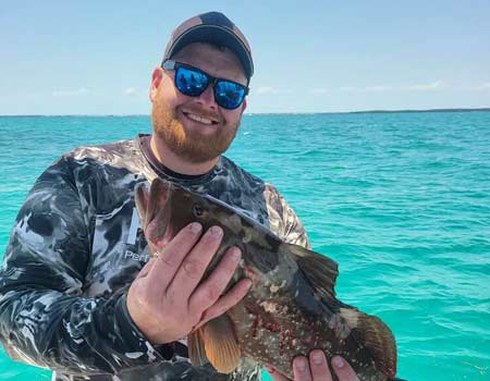Man holding a fish on a boat in Islamorada with Beyond Blessed Charters.