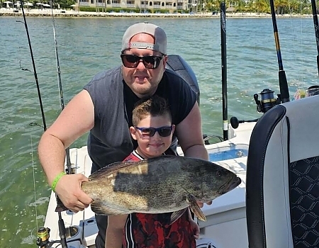 Man and child holding a large fish on a boat in Key Largo with Beyond Blessed Charters.