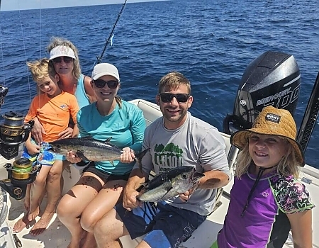 Family on a boat holding fish caught during Florida Keys fishing charters.