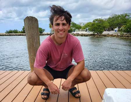 Man crouching on a dock near the water after inshore fishing in Islamorada.