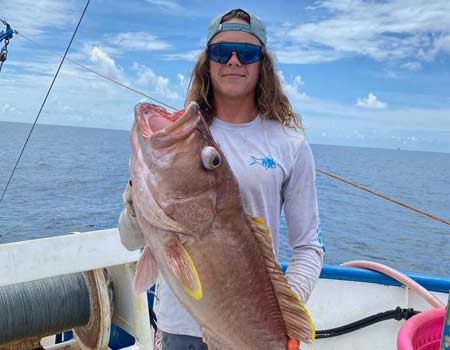 Man holding a large fish on a boat in Key Largo with Beyond Blessed Charters.