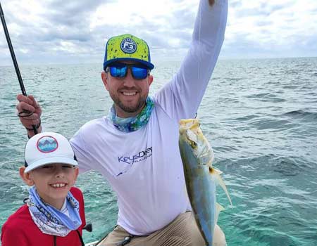 Man and boy holding a fish on a boat during an Islamorada boat tour.